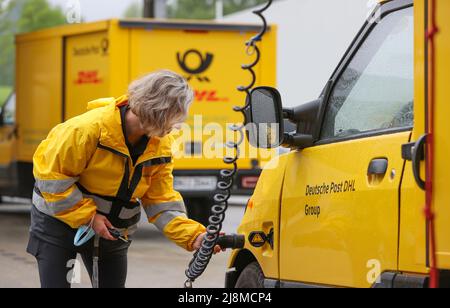 Saxony, Eibenstock: 17 May 2022, A Deutsche Post DHL Group delivery driver unplugs her electric-powered vehicle (Streetscooter) on the grounds of a climate-neutral delivery base before driving off. The new building offers optimal conditions for handling increasing parcel and merchandise mail volumes, is also climate-neutral and was ceremoniously handed over on the same day. In addition to underfloor heating with a heat pump, the building has a photovoltaic system that generates much of the energy needed for daily operations. Any additional energy required to charge the electric vehicles is sou Stock Photo