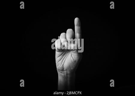 Dramatic black and white image of Index Pointing Up emoji isolated on black background Stock Photo