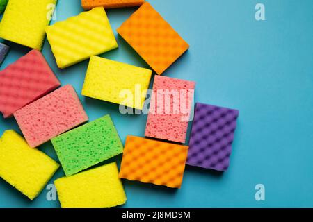 plenty of different multicolored sponges on blue background, top view Stock Photo