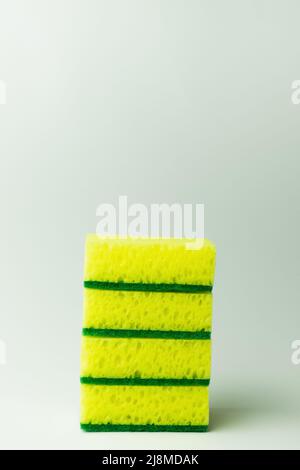 stack of porous yellow and green sponge scourers on grey background Stock Photo