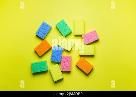 plenty of bright multicolored sponges on yellow background, top view Stock Photo