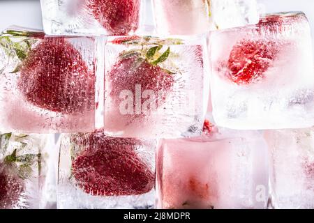 Fresh strawberries frozen in ice cubes - Close up. Stock Photo