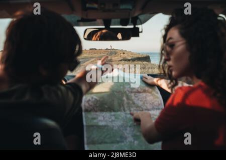 Back View of Man and Woman Sitting in the Car and Checking Map, Young Couple Enjoying Road Trip Stock Photo