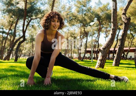 Sport and people concept. Photo of athletic female stretch after workout city park, outdoors. Beautiful sportswoman doing stretching exercises outdoor Stock Photo