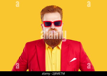Funny stylish extravagant bearded chubby man pretending to be serious on vivid yellow background. Stock Photo