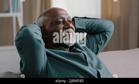 Calm serene elderly adult African American man relaxing with eyes closed take break relax at home office, old grandpa enjoying rest feel peace Stock Photo