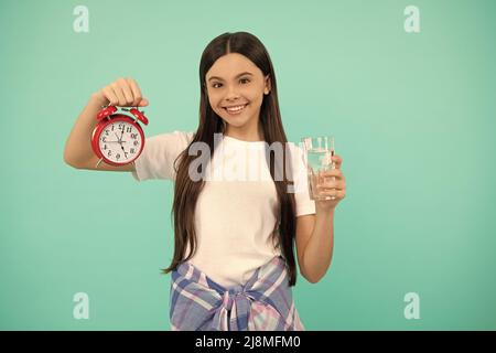 happy kid hold glass of water and clock to stay hydrated and keep daily water balance, thirst. Stock Photo