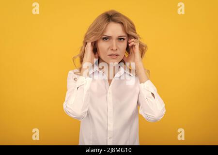 Unhappy ill woman touch ears suffering from ear pain yellow background, earache Stock Photo