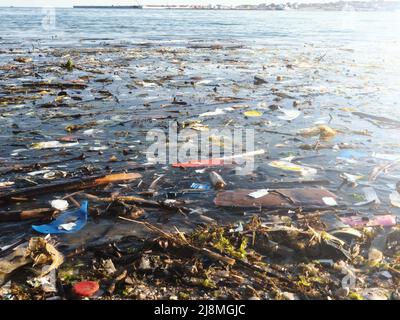 Plastic debris on blue sea surface. Polluted beach. Garbage, bottles and other plastic debris in ocean water. Stock Photo