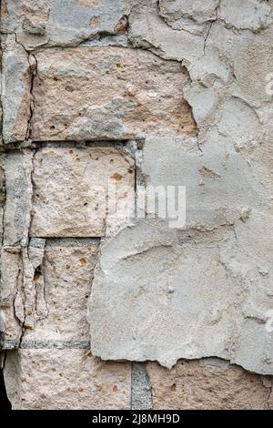 White brick plastered wall crumbling plaster, visible white and part of the old bricks. Crumbling brick wall with cracks Stock Photo