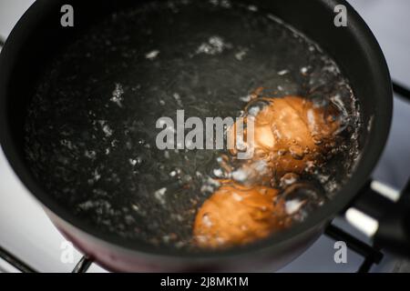 Two brown eggs in a pot of boiling water Stock Photo
