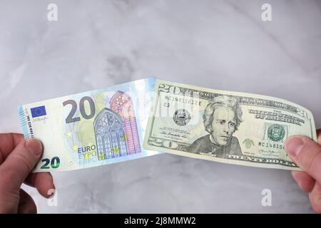 Banknotes of 20 euros and 20 US dollars in hands for comparison Stock Photo