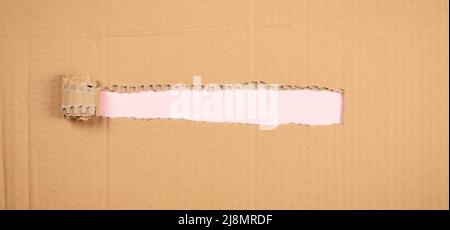 Hole ripped in brown corrugated cardboard. Blank ripped kraft carton with torn copy space for text. Top view Stock Photo