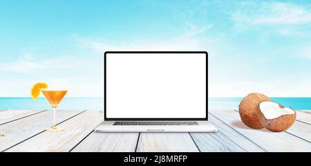 Laptop with isolated, clean display on wooden desk with sea in background Stock Photo
