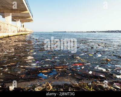 Plastic debris on blue sea surface. Polluted beach. Garbage, bottles and other plastic debris in ocean water.