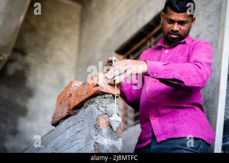 Construction labour checking level or straightening of wall using plumb bob vertical measuring tool at site - concept of professional skilled daily Stock Photo