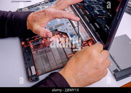 a computer repairman disassembles, repairs and does preventive maintenance for a broken laptop. Stock Photo