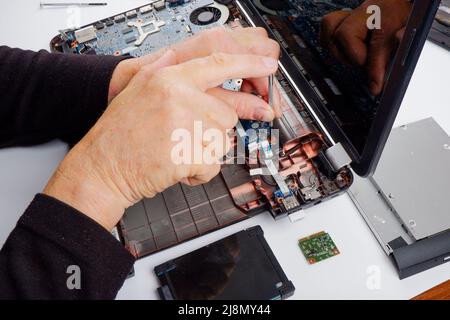 a computer repairman disassembles, repairs and does preventive maintenance for a broken laptop. Stock Photo