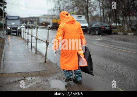 Workers on road. Road workers clean up garbage. People in orange clothes. Transport service maintains side of highway. Stock Photo