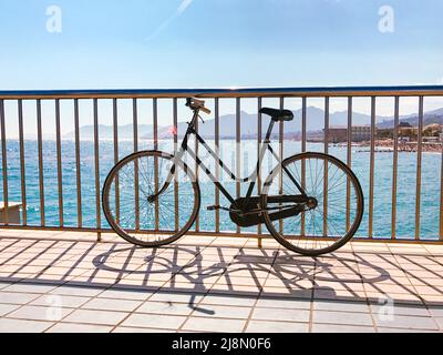 Panorama of the Ligurian coast with the sea and an old bicycle from the pier of Pietra Ligure, Savona, Italy Stock Photo