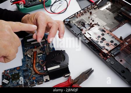 a computer repairman disassembles, repairs and does preventive maintenance for a broken laptop. Stock Photo