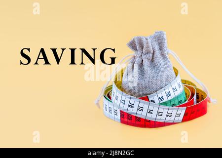 a small canvas bag with word SAVING wrapping with a centimetre on a yellow background Stock Photo