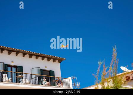 Low angle view of seaplane Canadair flying over hotel against clear blue sky Stock Photo