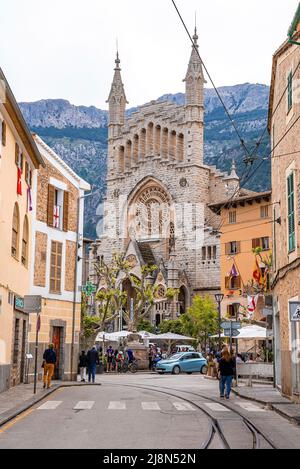 Railroad tracks by Church of Sant Bartomeu de Soller in city against mountain Stock Photo