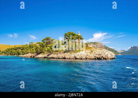 Trees growing on cliff by lighthouse at Mediterranean seaside against blue sky Stock Photo