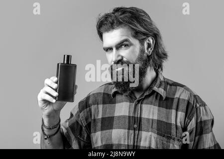 Expert care for demanding hair. Plastic container with shampoo. Young handsome man applying cream lotion. Man holds bottle of shampoo or shower gel Stock Photo