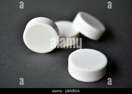 White large round tablets on a gray background. Medicines. Stock Photo