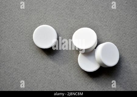 White large round tablets on a gray background. Medicines. Stock Photo