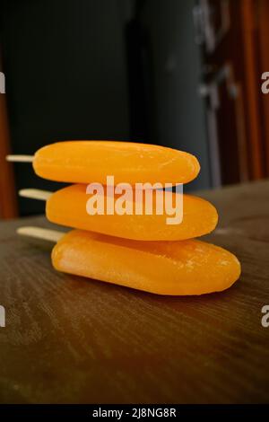 closeup the bunch orange color and flavor stick ice cream over out of focus black brown background. Stock Photo