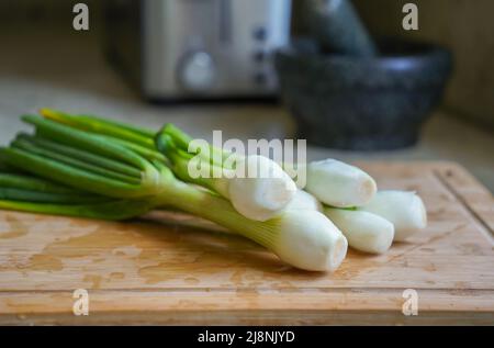 Spring Onions cleaned on a wooden cutting board Stock Photo