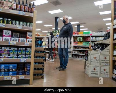 Kirkland, WA USA - circa March 2022: View of an older man shopping for beer in the alcohol section of a Trader Joe's grocery store. Stock Photo