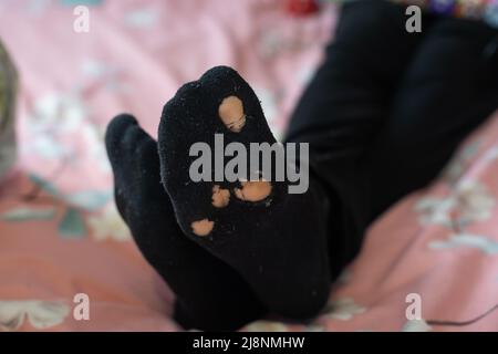 leaky socks on a man's leg on old pink background Stock Photo