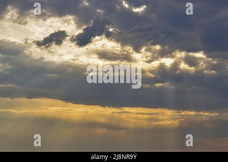 Sunlight breaks through the storm clouds. Cloudy sky at sunset. Sky And Clouds Background. Stock Photo