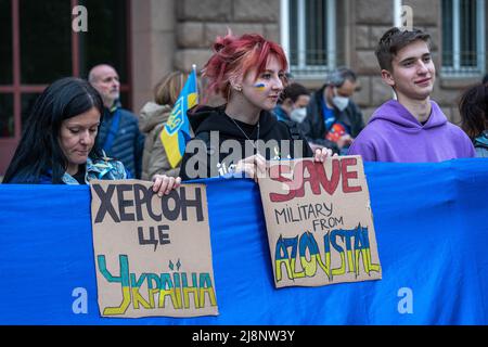 Sofia, Bulgaria - April 28, 2022 - Three persons stand in a row, holding Ukrainian flag and slogans Save Military from Azovstal and Kherson is Ukraine Stock Photo