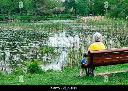 Montreal, CA - 16 May 2022: Senior woman sitting on a bench in Montreal Botanical Garden Stock Photo