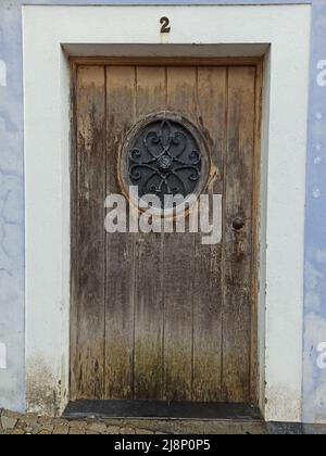 Old shabby wooden door with wrought iron elements and inserts on the island of Terceira Stock Photo