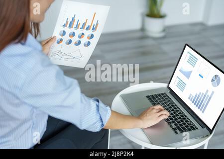 self employed, business owner, pleasure from work, Asian woman using computer holding financial documents to check or plan budget, manage investment Stock Photo