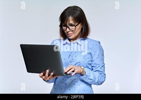 Middle age business woman using laptop, on light background Stock Photo