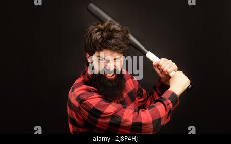 Angry bearded man in plaid shirt swing baseball bat. Sport equipment. Violence, attack, aggression. Stock Photo