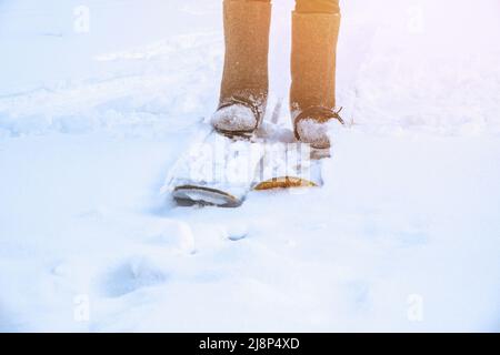 A man in felt boots on homemade skis walks through the snow into the forest. Hiking, traveling, hunting, fishing. Stock Photo