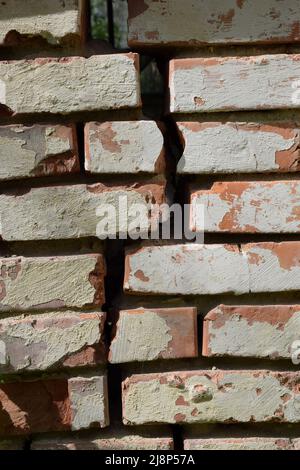 Old brick wall with a vertical crack and peeling plaster Stock Photo