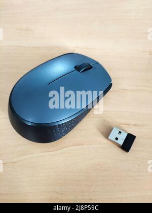 Wireless computer mouse with USB adapter on a wooden background. View from above Stock Photo