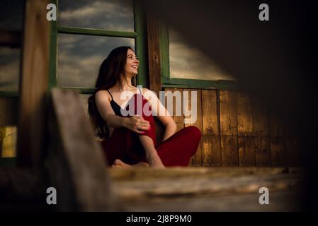 Young woman sit in front of a rise and smiling Stock Photo