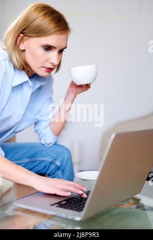 Businesswoman working on laptop at home and drinks hot coffee espresso Stock Photo