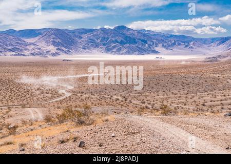Vehicles travel down the gravel road towards the Racetrack Playa in Death Valley National Park Stock Photo