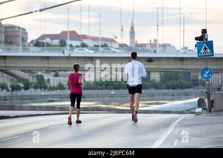 Young man and woman jogging in the city, rear view Stock Photo